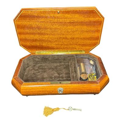 Sale Photo Thumbnail #198: Made by Reuge, in Italy. This piece has fine marquetry inlay in a floral motif, and an internal music box. Includes the original key. Measurement; 12”L x 6.5”W. Pre-auction estimate: $100-$150. [JP]