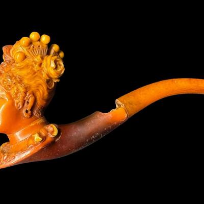 Sale Photo Thumbnail #226: Two pieces. Each is hand carved. One is unused. The amber colored piece has a crack (pictured), and may have been previously used. Two pipe stands are also included. Measurement of longest pipe: 5.75”L. [JP]