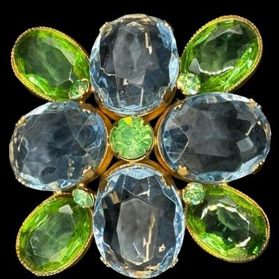 Sale Photo Thumbnail #233: This Modernist gold tone brooch is signed “Les Bernard.” It features nine green stones and four cornflower blue stones. Each stone is bezel set. Measurement: 2” x 2”. [JP]