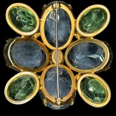 Sale Photo Thumbnail #234: This Modernist gold tone brooch is signed “Les Bernard.” It features nine green stones and four cornflower blue stones. Each stone is bezel set. Measurement: 2” x 2”. [JP]
