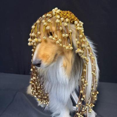 Sale Photo Thumbnail #291: This piece is in the style of a 1920s Flapper headdress. It is gold in color, and features beads throughout. The skull cap is woven. The beaded fringe is intact. Measurement: 16”L. [JP]