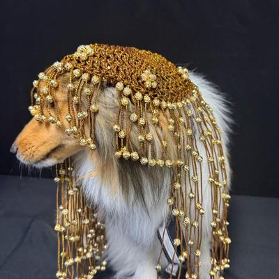 Sale Photo Thumbnail #290: This piece is in the style of a 1920s Flapper headdress. It is gold in color, and features beads throughout. The skull cap is woven. The beaded fringe is intact. Measurement: 16”L. [JP]