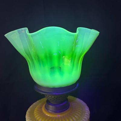 Sale Photo Thumbnail #301: This lamp was electrified at one time. It features an opaque lemon-yellow glass font, and a reeded brass column with a yellowish, opalescent, UV reactive, ruffled glass shade. Measurement: 24”H x 9”W. Pre-auction estimate: $100-$200. [JP]