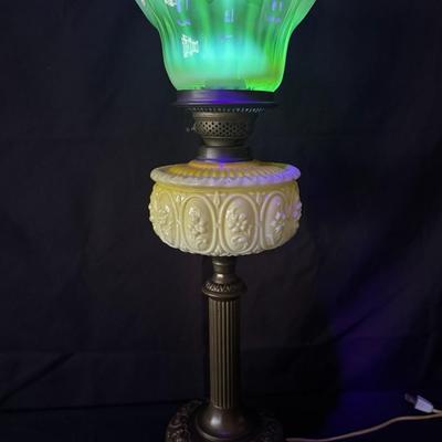 Sale Photo Thumbnail #300: This lamp was electrified at one time. It features an opaque lemon-yellow glass font, and a reeded brass column with a yellowish, opalescent, UV reactive, ruffled glass shade. Measurement: 24”H x 9”W. Pre-auction estimate: $100-$200. [JP]