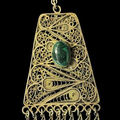 Sale Photo Thumbnail #334: [26.25g] This piece is marked “Israel, 925.” It features stunning filigree work, and has a green stone cabochon. There is a gold vermeil wash on this pendant. Measurement: 3.25”H x 2”W. [JP]