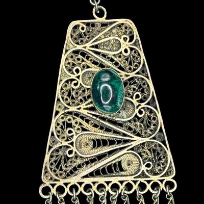 Sale Photo Thumbnail #333: [26.25g] This piece is marked “Israel, 925.” It features stunning filigree work, and has a green stone cabochon. There is a gold vermeil wash on this pendant. Measurement: 3.25”H x 2”W. [JP]