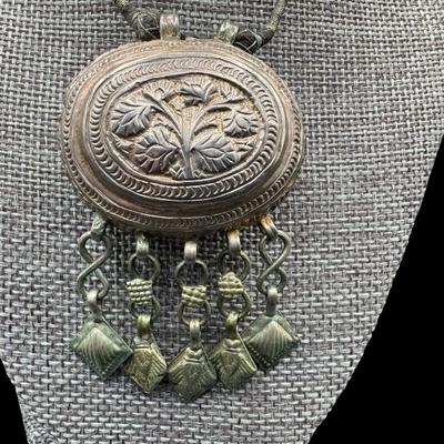 Sale Photo Thumbnail #350: [28.50g] This is believed to be a prayer box. It is on the original cord. There is age related wear. The weight is approximate, and does not include the cord. Measurement: 1.75”W x 3”H. Silver content confirmed using Niton XRF precious metals analyzer