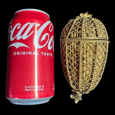 Sale Photo Thumbnail #416: Constructed of brass filigree with a teardrop or egg shaped design. It is hinged with a clasp and findings on either end. The lining inside show wear, although the integrity of the piece is solid. Measurement: 5”H. Pre-auction estimate: $100-$200. [JP]