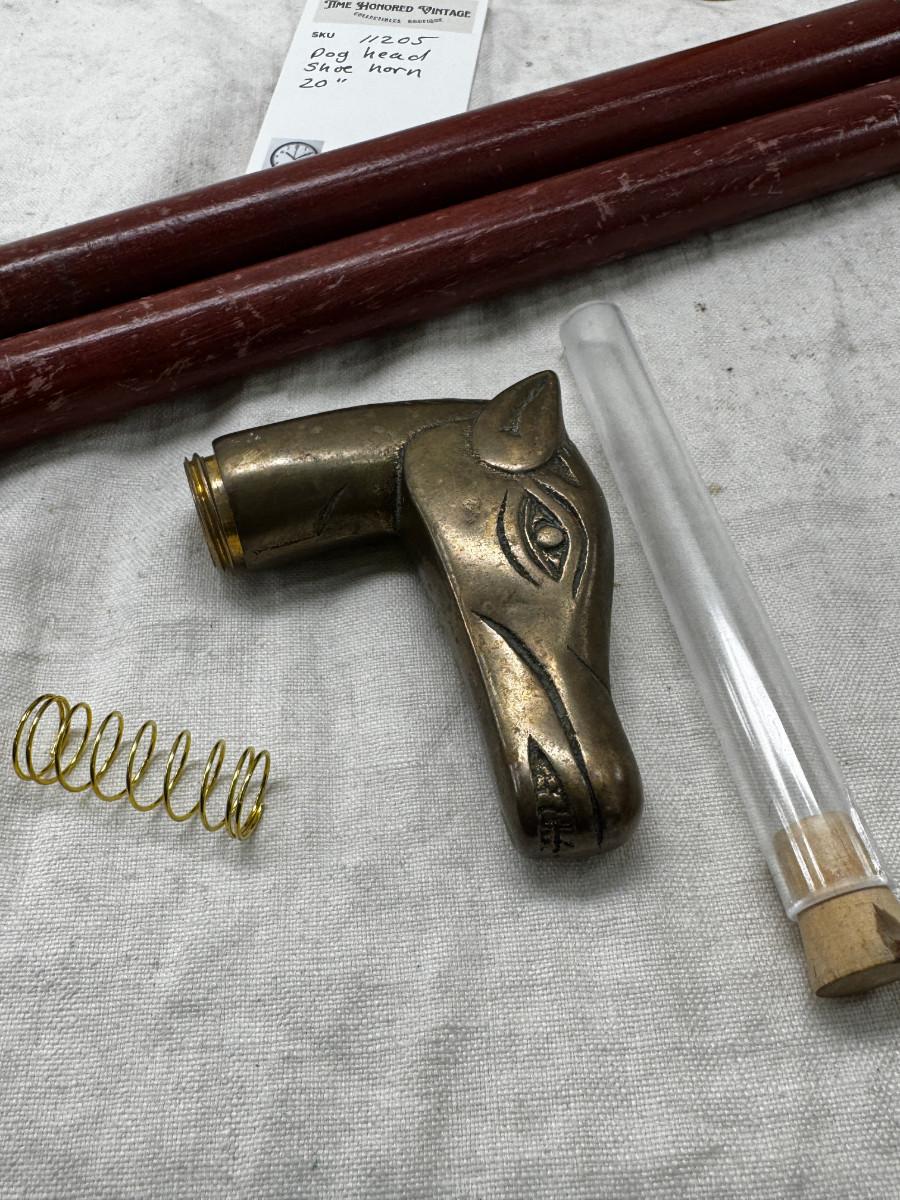 Sale Photo Thumbnail #549: Dog head (resin) with shell horn, marked with a drop of paint, Taiwan Brass Dog head stick breaks apart and top containes a corked glass vial , under that is a spring, and then the bottom third screws off too!
