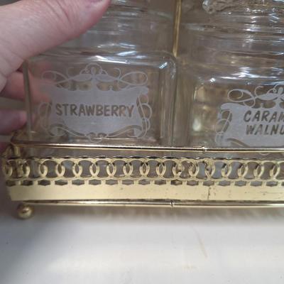set of four glass apothecary jars in gold tone metal holder caddy, jars have etched design see all photos.