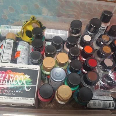 container of various craft paints and supplies. Container has lid but lid doesn't fasten down.