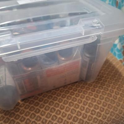 container of various craft paints and supplies. Container has lid but lid doesn't fasten down.