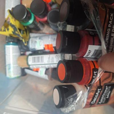 container of various craft paints and supplies. Container has lid but lid doesn't fasten down.