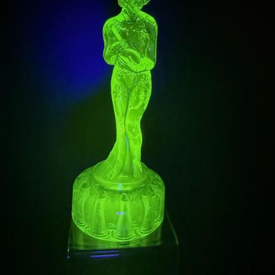 Sale Photo Thumbnail #168: Bashful Charlotte, uranium glass  made by Cambridge Glass Co, 1930s
Has 10 holes for flowers ,depicts nude figure holding a flask
9 inches tall
Very good condition