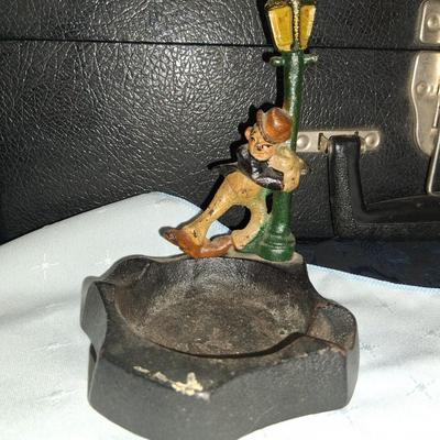 Sale Photo Thumbnail #9: This amazing ashtray features a young gentleman hanging on to the lamp post as he dances in the Rain like Fred Astaire. Good condition with some discoloration to the front as pictured