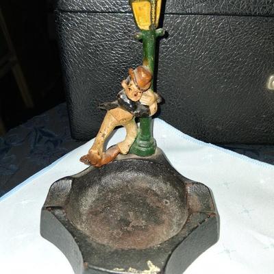 Sale Photo Thumbnail #7: This amazing ashtray features a young gentleman hanging on to the lamp post as he dances in the Rain like Fred Astaire. Good condition with some discoloration to the front as pictured
