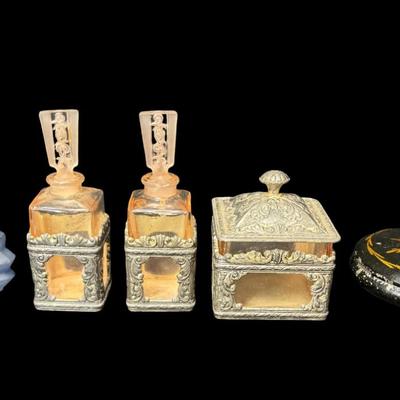 Sale Photo Thumbnail #562: Includes three perfumes, a silver tone trinket box with pink glass insert, and an enamelware Toleware metal trinket box. There is age related wear and minimal paint loss to the Toleware piece. The two pink perfume bottles have damaged stoppers. [BK]