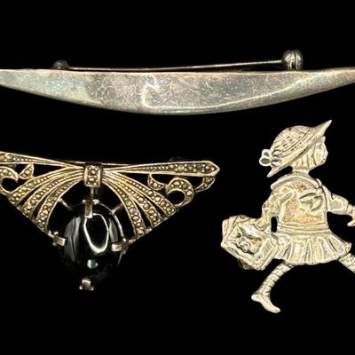 Sale Photo Thumbnail #617: [20.67g] Includes a black onyx and marcasite brooch, a brooch made in Mexico that depicts a young girl, and more. Total of three pieces. Measurement of longest: 3.5”L. Silver content confirmed using Niton XRF precious metals analyzer. [BK]