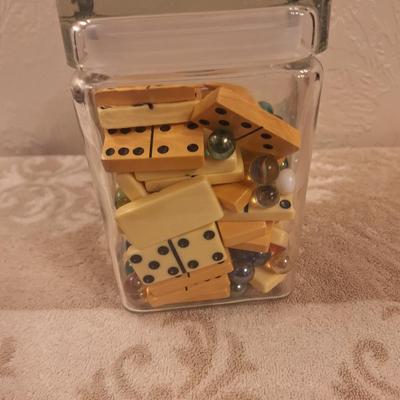 glass jar with 2 sets of dominoes and various glass beads or marbles