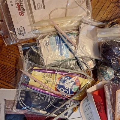 assortment of knitting or crocheting supplies, needles, little bit of yard and a few patterns