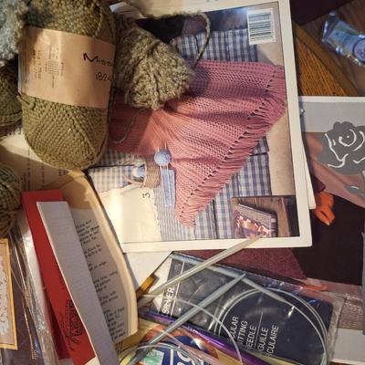 assortment of knitting or crocheting supplies, needles, little bit of yard and a few patterns