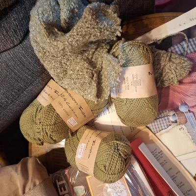 assortment of knitting or crocheting supplies, needles, little bit of yard and a few patterns
