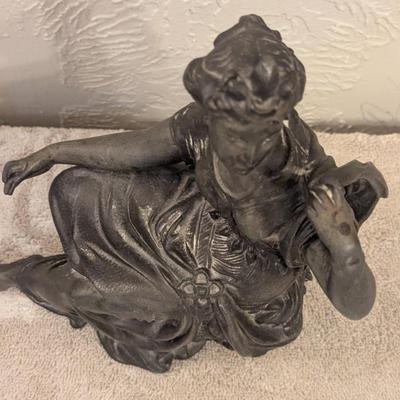 cast metal spelter clock topper of woman seated, Greek goddess maybe? Diana Artemis or Pandora? We aren't sure.