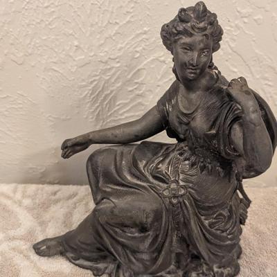 cast metal spelter clock topper of woman seated, Greek goddess maybe? Diana Artemis or Pandora? We aren't sure.