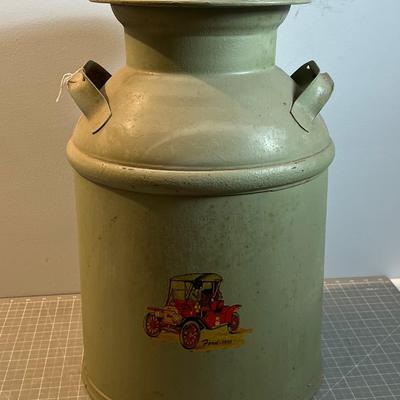 Old Milk Can that has been Painted and has Car Stickers on it. 