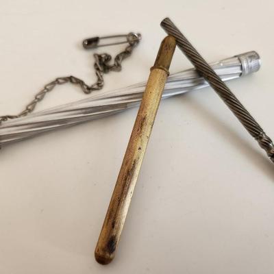 Sale Photo Thumbnail #307: This lot is for a Trio of Vintage Needle Cases.  These nifty little items from the past are needle (or possible pencil lead) holders.  The brass one has a selection of needle within.  The aluminum case has a chain with a safety pin - a very utilitarian pi