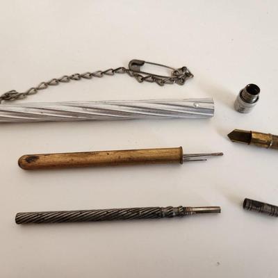 Sale Photo Thumbnail #306: This lot is for a Trio of Vintage Needle Cases.  These nifty little items from the past are needle (or possible pencil lead) holders.  The brass one has a selection of needle within.  The aluminum case has a chain with a safety pin - a very utilitarian pi