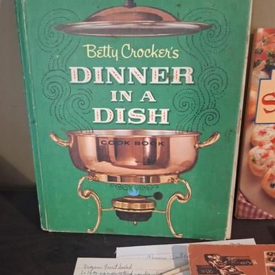 vintage cookboox and pamplets, the stoneware book has been heavily used- it has a bend to it.