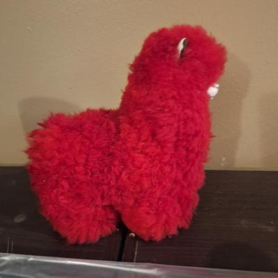 This is a red, handmade alpaca fur plush toy. 