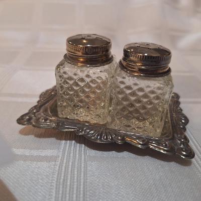 very small glass salt ad pepper shaker in silver plated tray
