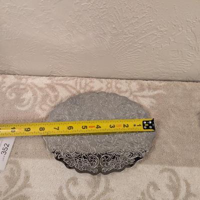 silver toned metal trivet with floral scroll pattern