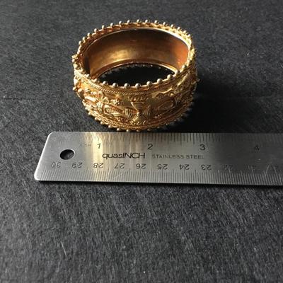 Wide hinged yellow gold tone bangle bracelet with floral and scroll motifs