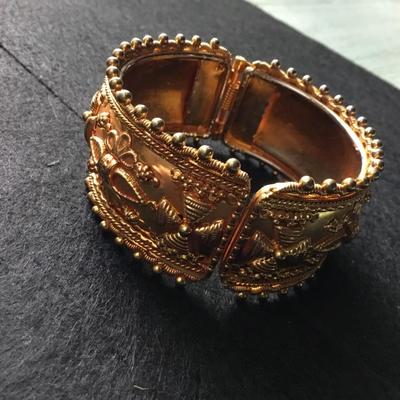 Wide hinged yellow gold tone bangle bracelet with floral and scroll motifs