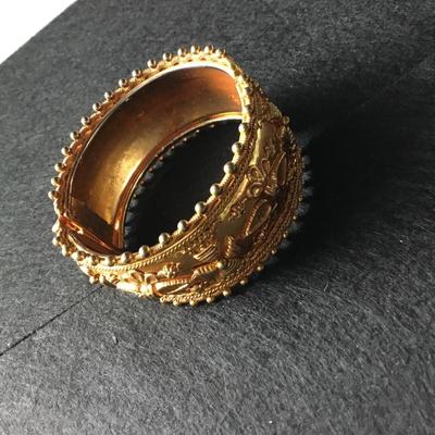 Wide hinged yellow gold tone bangle bracelet with floral and scroll motifs