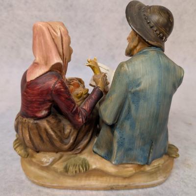 Sale Photo Thumbnail #222: Norleans Japan Porcelain Figurine 
Depicts man sitting down w/ a hat, pipe and book and a woman holding a basket 
7x8x4