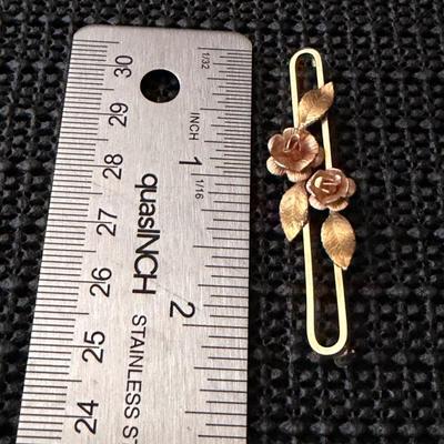 vintage Krementz gold-tone bar brooch featuring a rose and leaf motif.