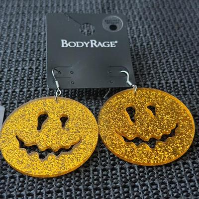 Body Rage glitter pumpkin drop earrings made of acrylic material.