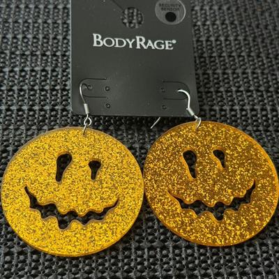 Body Rage glitter pumpkin drop earrings made of acrylic material.
