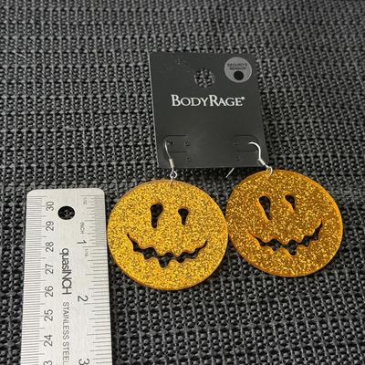Body Rage glitter pumpkin drop earrings made of acrylic material.