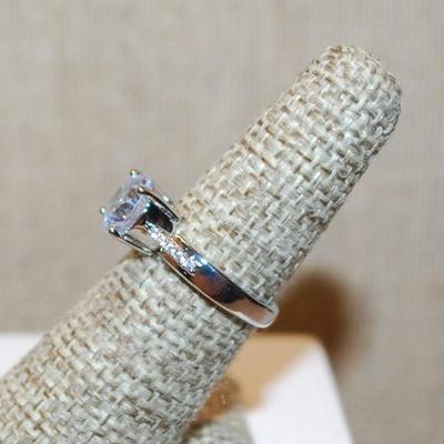 Size 6 Single Round Clear Stone Ring with Faint Line Accents on a Silver Tone Band (3.4g)