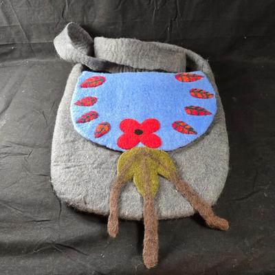 Sale Photo Thumbnail #457: This lot is for a Hand Made Felted  Grey Purse with Blue Cover and Floral Accents.  It has a very long shoulder strap.  Long enough to be knotted up to desired length.  With straps it measures about 38-inches long x 13-inches wide.  It does have a zippere
