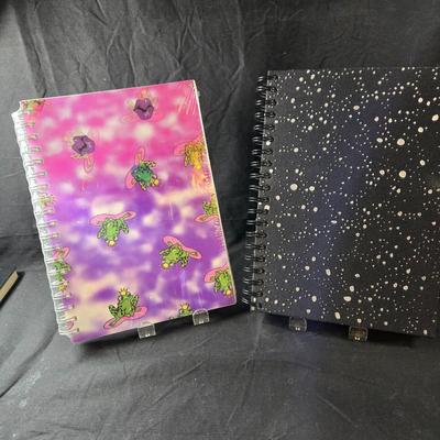 Sale Photo Thumbnail #499: This lot is for Spiral Bound New Journals. This is a pair of Spiral Bound Journals with unlined pages.  One has a Frogs and Kisses holographic cover and the other is a black background with sparkle dots like the night sky,  Unused.  They are both about 7-