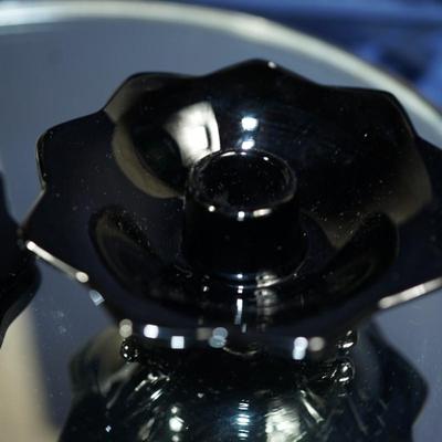 Sale Photo Thumbnail #76: classic glass black amethyst candle holders. 
smooth pedal edge/three footed base with center pedestal 
very good condition
light tested for the purple color held to light.