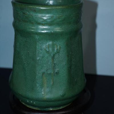 Sale Photo Thumbnail #100: Early 1900's Zanesville pottery vase. 
Matt Green, panelled sides with a flower on every other panel. 
No factory marks found. 
Height: 7 1/4" 
Opening: 4 3/4" 
condition. Good. no cracks or chips noted. There are a tiny specks of where sand from the kiln