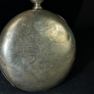 Sale Photo Thumbnail #128: antique pocket watch. silverplated /case coin? 
Case: 52810
no markings found inside the works, 
bezel and crystal intact and in good condition 
key wind- key is missing, 
The watch is selling as is. Not working 
engraved case of trees and cottage on one 