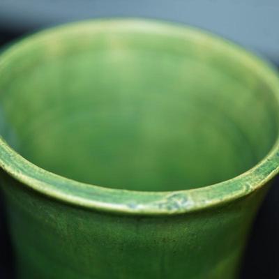 Sale Photo Thumbnail #179: a 12" vintaGE cyclinder form vase. matt green slip glaze with yellow color. 
The base is a yellow clay glazed. 
no markings found. 
Good condition. a few factory flaws along the top edge but these are not chips. 
Very classic looking piece.